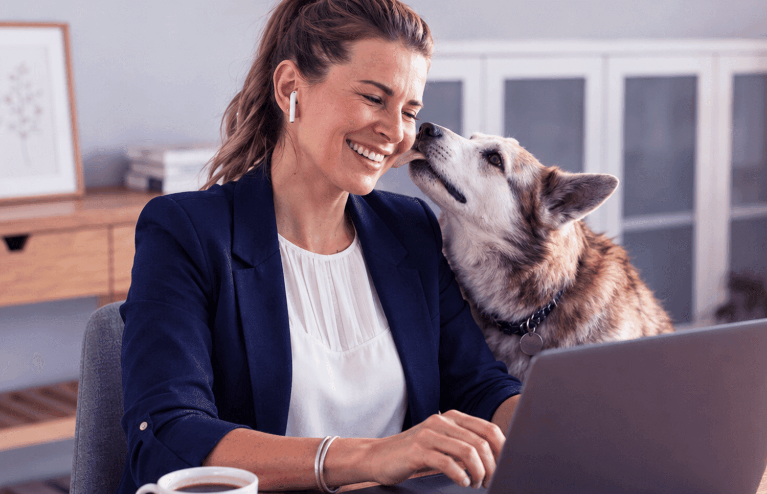 Woman using a laptop at home with her dog beside her